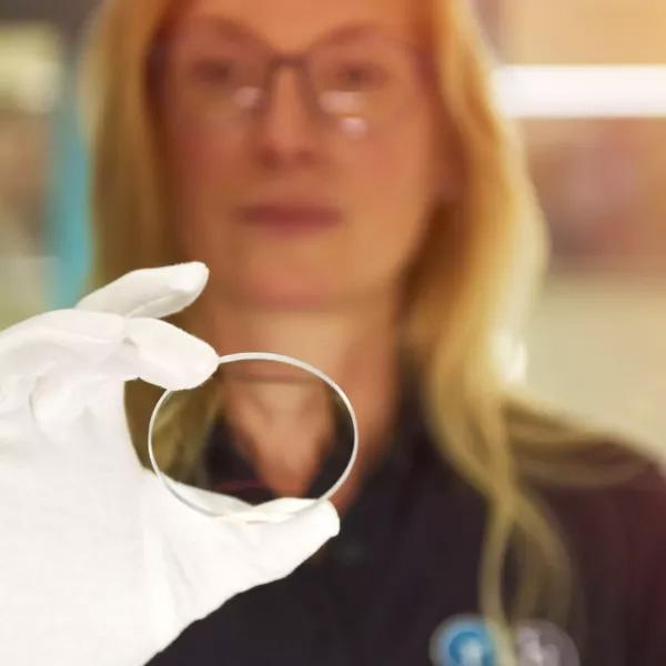 Rupp-und-Hubrach-Brillenglas Frau hält Brillenglasrohling in der Hand