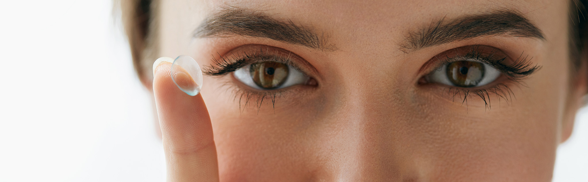 Kontaktlinsen_Gesicht Frauengesicht mit Kontaktlinse auf dem Zeigefinger