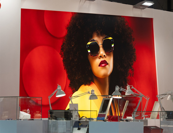 MIDO Messestand: Frau mit großer Sonnenbrille auf einer Plakatwand